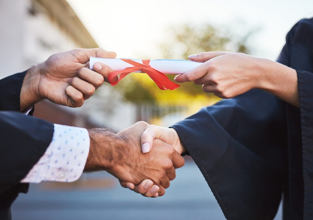 instructor handing a man his diploma while shaking his other hand