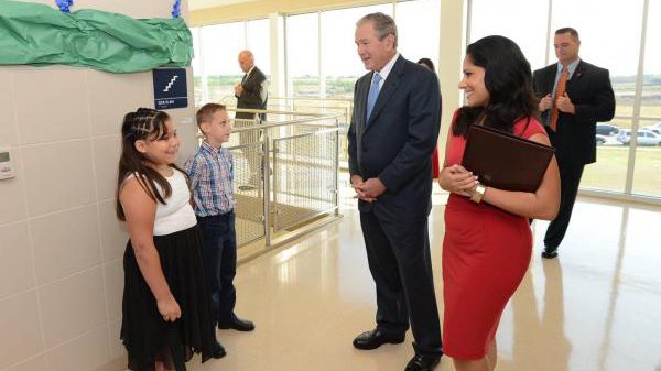 Charlie Teague, background right, stands guard for former President George W. Bush, center. (Courtesy: Mitchell News-Journal)