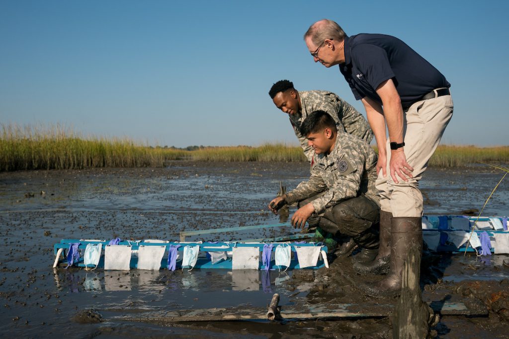 Cadets Jerry Higgins and Douglas Karam, accompanied by Dr. John Weinstein, Biology, deploy an experiment to measure how face masks, rubber gloves and hand wipes decompose in the salt marsh behind Inouye Hall on Thursday, October 14, 2021. Credit: Cameron Pollack / The Citadel