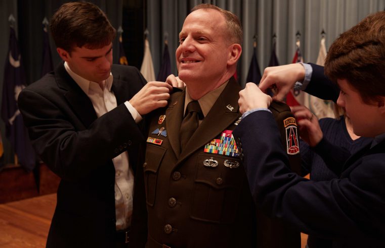 U.S. Army Reserve Maj. Gen. John Phillips smiles as his sons Ryan and Stone pin the two-star insignia to the shoulders of his Army Green Service Uniform during his promotion ceremony held in Alexander Hall, Fort Gordon, Ga. Feb. 9, 2020.