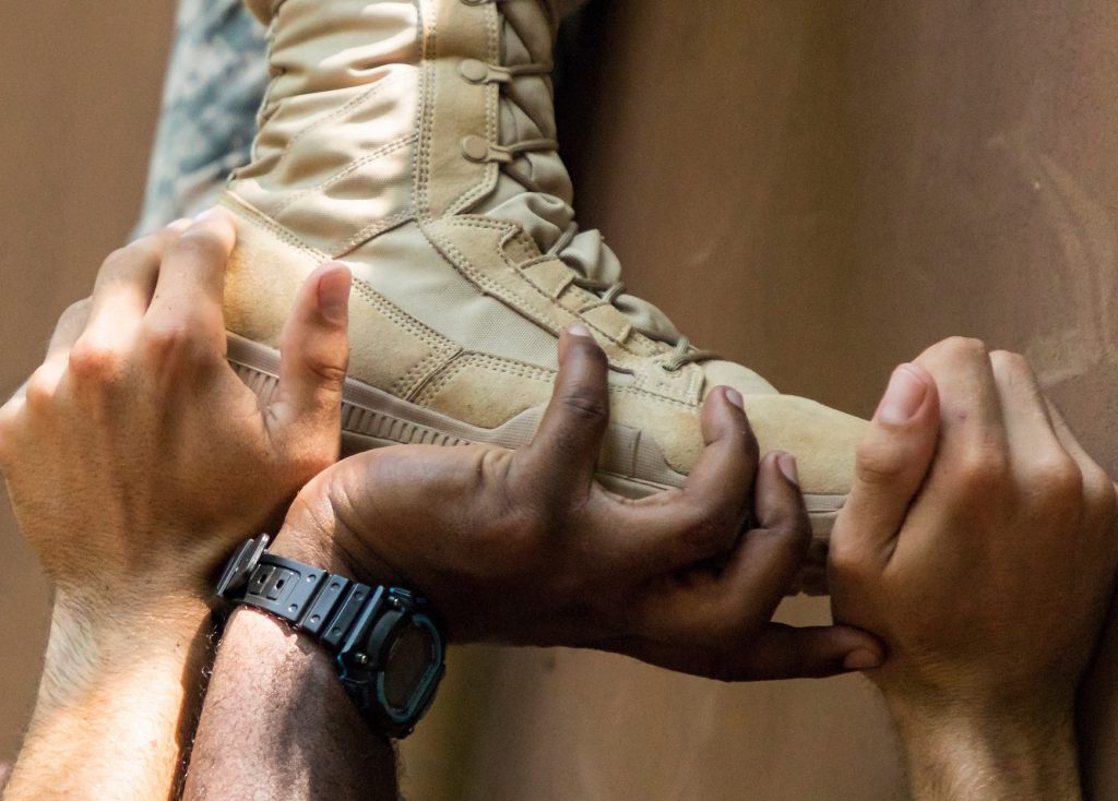 Hands supporting a foot in a military boot